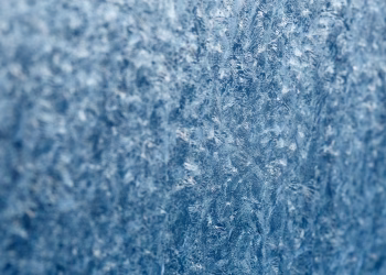 Detailed macro shot of intricate frost texture on a window during winter.