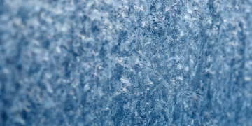 Detailed macro shot of intricate frost texture on a window during winter.