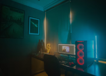 A dimly lit minimalist gaming setup featuring a desktop PC and neon lights.