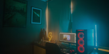 A dimly lit minimalist gaming setup featuring a desktop PC and neon lights.