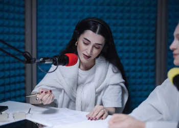 Two women hosting a radio show, using professional microphones in a soundproof studio.