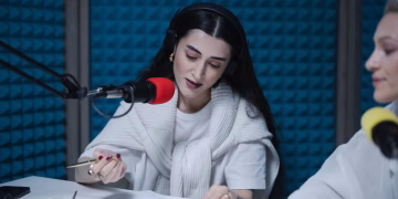 Two women hosting a radio show, using professional microphones in a soundproof studio.