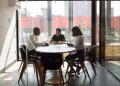 Three professionals collaborating in a modern office boardroom setting during daylight.