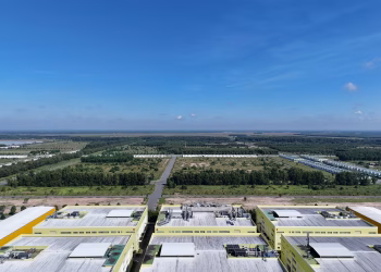 Aerial shot of industrial buildings and green landscape in Bình Dương, Vietnam under a clear blue sky.