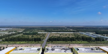 Aerial shot of industrial buildings and green landscape in Bình Dương, Vietnam under a clear blue sky.