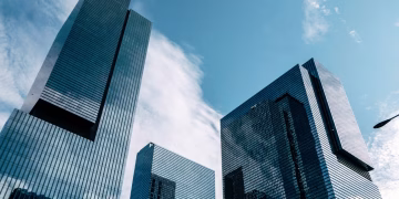 Low-angle view of modern skyscrapers reaching into a clear blue sky, capturing urban architecture.