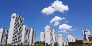 Skyline of high-rise apartments in Yongin with clear blue sky and clouds.
