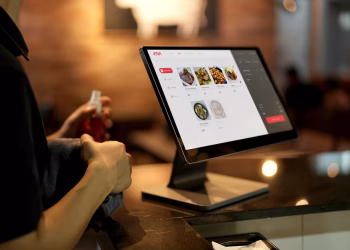 A person using a touchscreen ordering system in a modern restaurant setting.