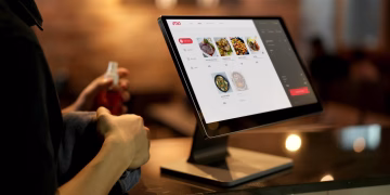 A person using a touchscreen ordering system in a modern restaurant setting.