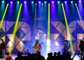 Energetic live band performance on stage with dynamic lighting at night.