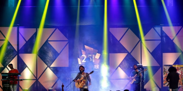 Energetic live band performance on stage with dynamic lighting at night.