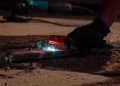 Detailed close-up of welding process with tool, sparks, and glowing metal.