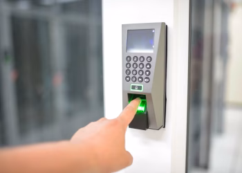 A person uses a fingerprint scanner for secure entry in a business setting.