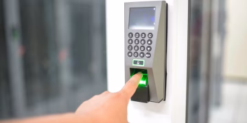 A person uses a fingerprint scanner for secure entry in a business setting.