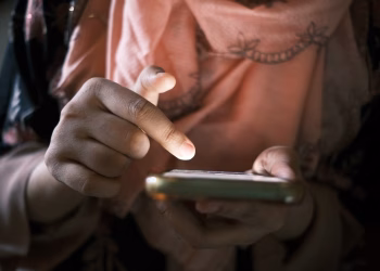 Close-up of hands using a smartphone indoors, highlighting touch technology.