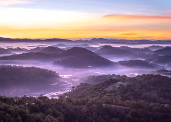 Capture the serenity of a misty mountain landscape at sunrise with vibrant colors and tranquil scenery.