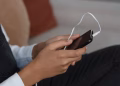 A person holds a smartphone with earbuds connected, capturing modern technology engagement.