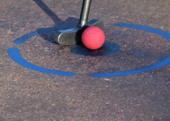 red golf ball on brown and white concrete pavement