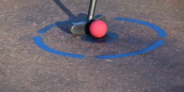 red golf ball on brown and white concrete pavement