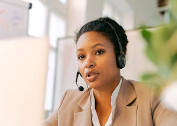 African American woman working in a call center with a headset on, providing customer support.