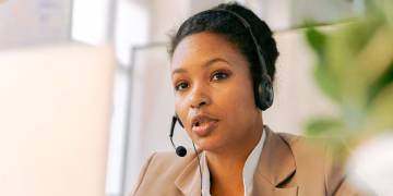 African American woman working in a call center with a headset on, providing customer support.