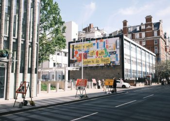 City street scene with a colorful billboard and road closure signs.