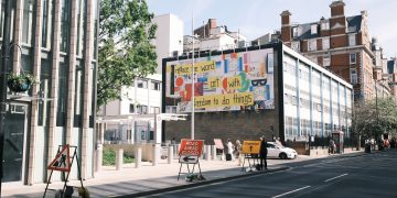 City street scene with a colorful billboard and road closure signs.