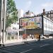 City street scene with a colorful billboard and road closure signs.