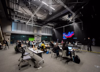 A diverse group attending an educational seminar with screens and seating indoors, highlighting collaboration.
