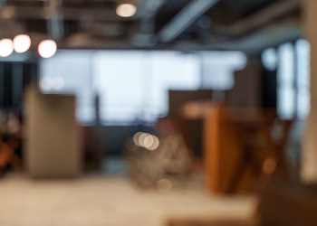Defocused view of an office space with soft lighting and bokeh effects creating a modern and abstract atmosphere.