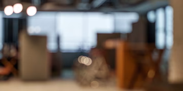 Defocused view of an office space with soft lighting and bokeh effects creating a modern and abstract atmosphere.