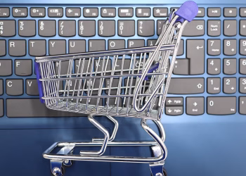 A miniature shopping cart placed on a laptop keyboard symbolizing online shopping and e-commerce.
