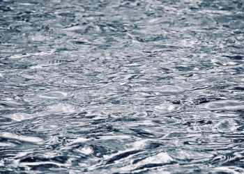 A detailed view of a water surface showing abstract rippling patterns and reflections.