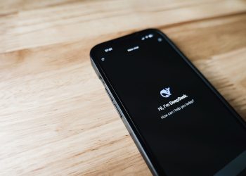 Hand holding smartphone indoors with blurred office background, focus on screen notifications.