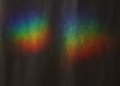 Vibrant rainbow colors from a light prism create an abstract display on a dark background.