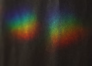 Vibrant rainbow colors from a light prism create an abstract display on a dark background.