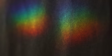 Vibrant rainbow colors from a light prism create an abstract display on a dark background.