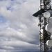 A telecommunication tower equipped with satellite dishes against a cloudy sky.