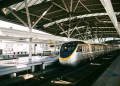 Commuter train awaits at a modern indoor station in Taiwan. Sunlight filters onto the platform.