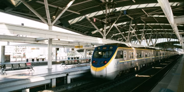 Commuter train awaits at a modern indoor station in Taiwan. Sunlight filters onto the platform.