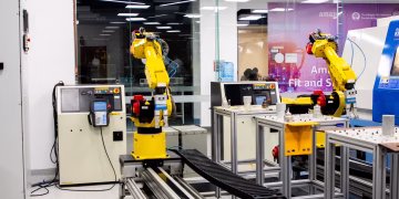 Robotic arms in action within a modern industrial control room setting, showcasing technology and production.
