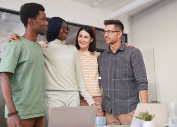 Four diverse colleagues sharing a moment of teamwork and collaboration in an office setting.