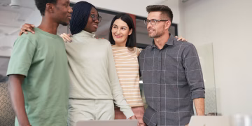 Four diverse colleagues sharing a moment of teamwork and collaboration in an office setting.
