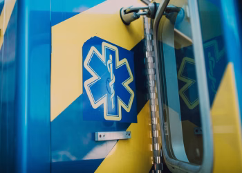Vibrant blue and yellow medic symbol on an ambulance door, representing emergency medical services.