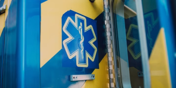 Vibrant blue and yellow medic symbol on an ambulance door, representing emergency medical services.