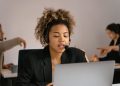 Customer support agent with headset working on laptop in office.