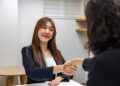 Businesswoman in professional attire shaking hands with recruiter in an office setting.