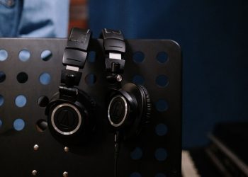 Close-up of professional headphones hanging on a perforated music stand in a studio setting.