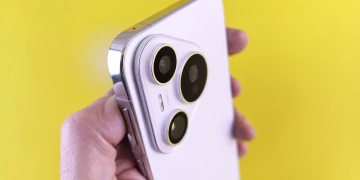 A close-up shot of a modern smartphone camera lens held against a bright yellow backdrop.