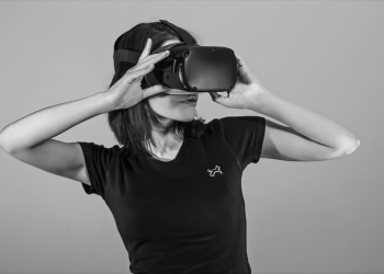 Black and white portrait of a young woman using a VR headset.